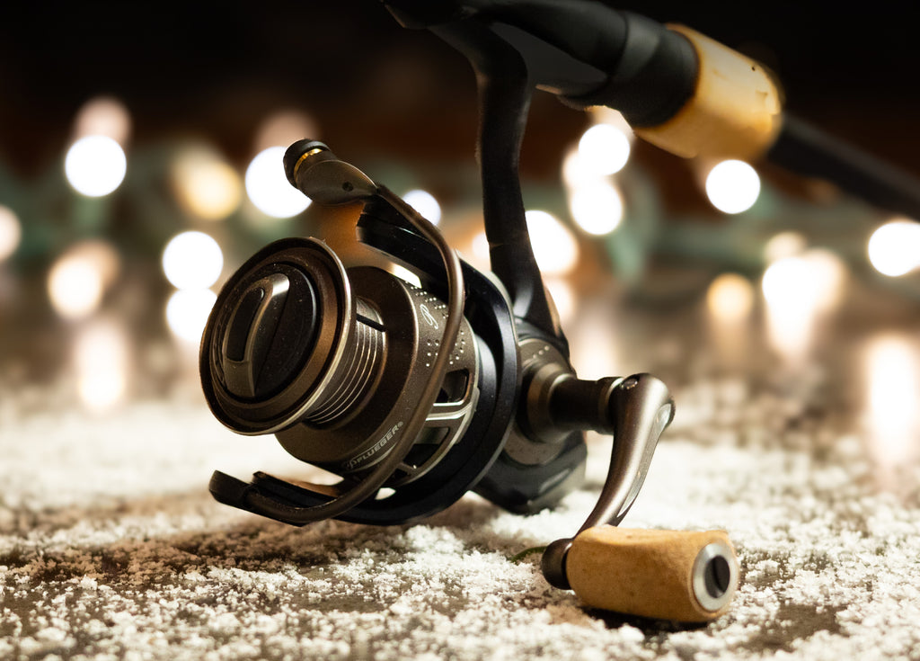 Close up of a Pflueger President Spinning Reel on a snowy ground with holiday lights